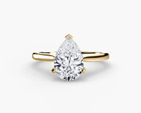 Gold ring with a pear-shaped diamond on a white background