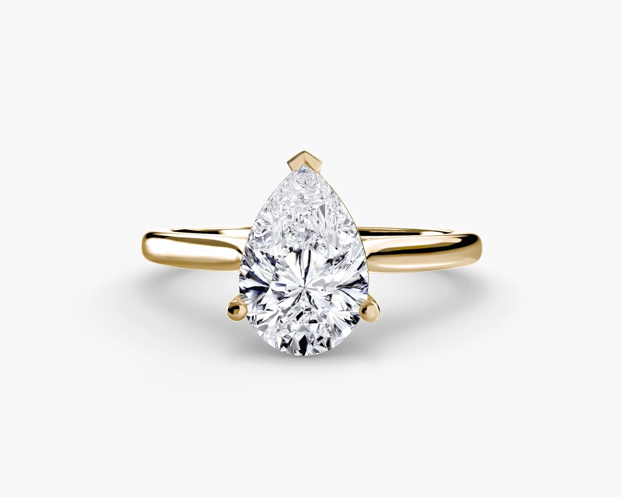 Gold ring with a pear-shaped diamond on a white background