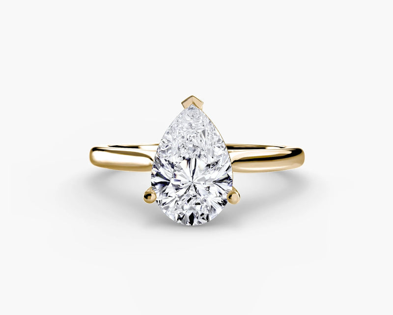 Gold ring with a pear-shaped diamond on a white background