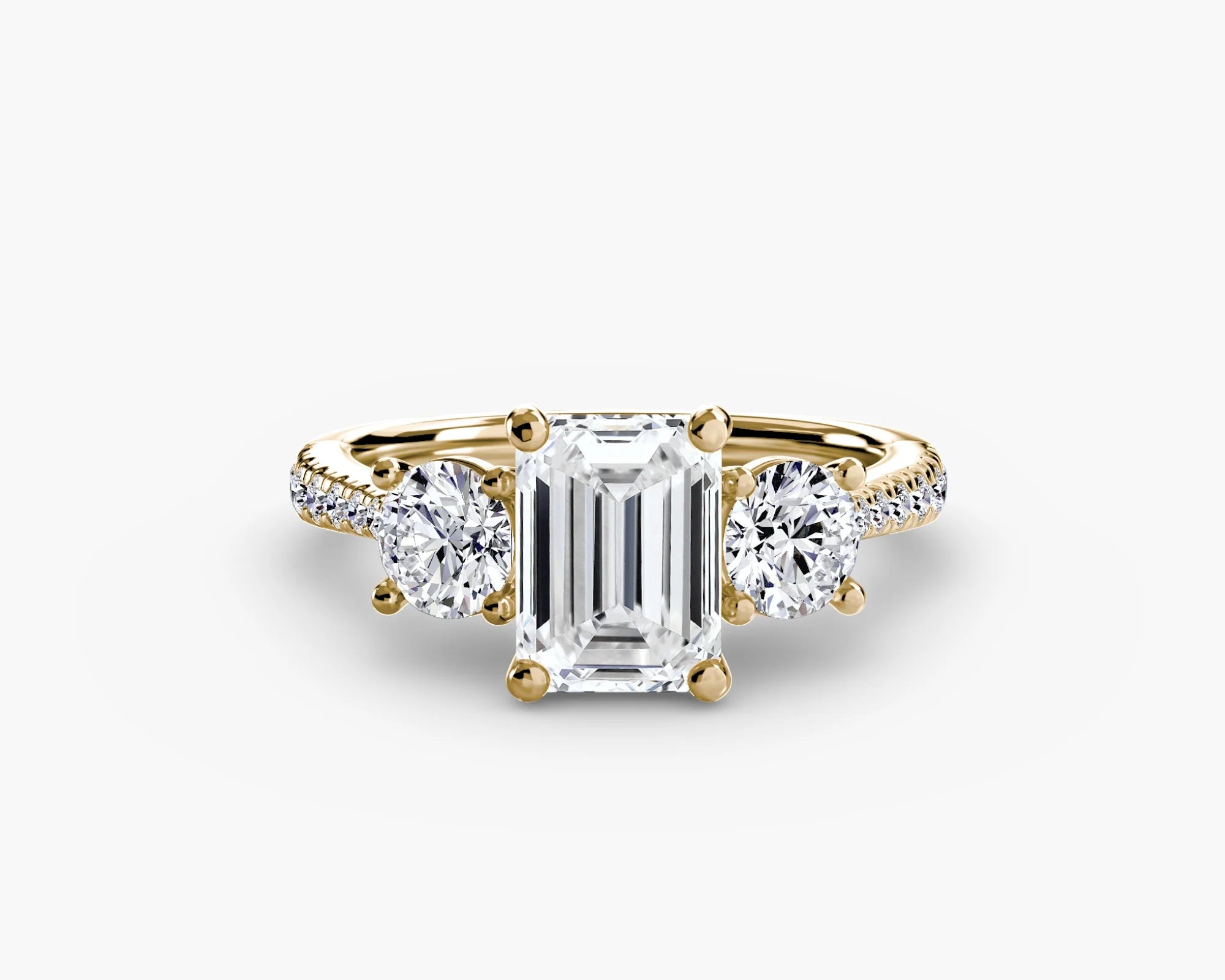 Gold ring with a central emerald-cut diamond and two side stones on a white background