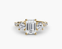 gold ring with a large emerald-cut diamond and smaller round diamonds on a white background