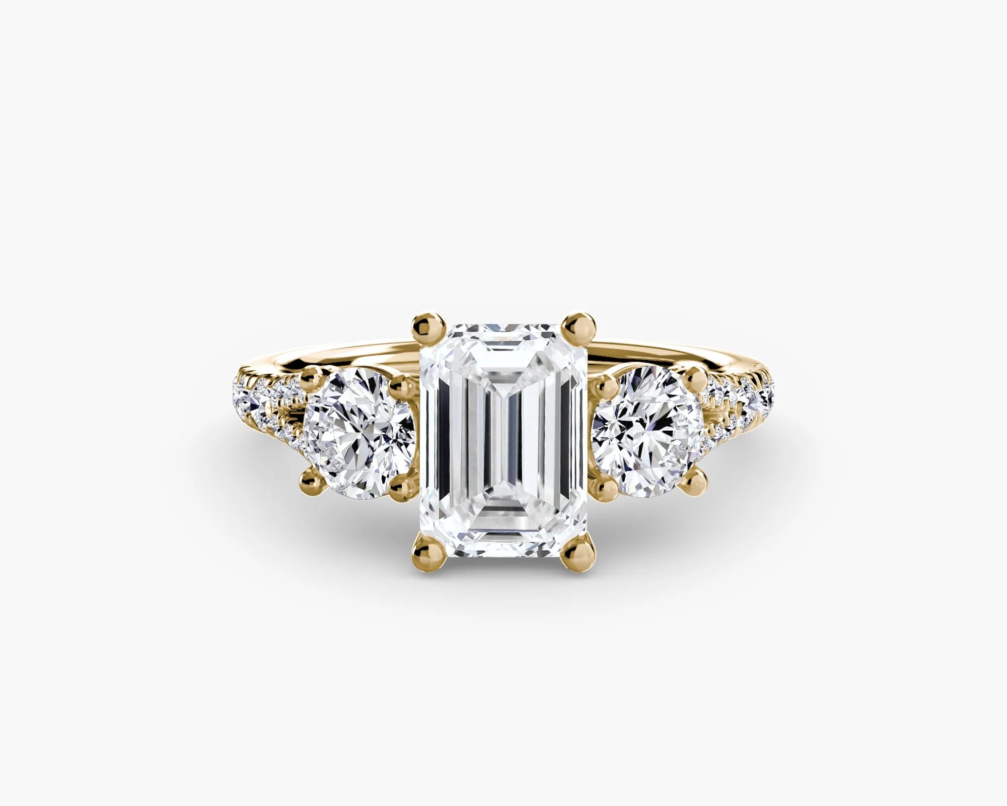 gold ring with a large emerald-cut diamond and smaller round diamonds on a white background