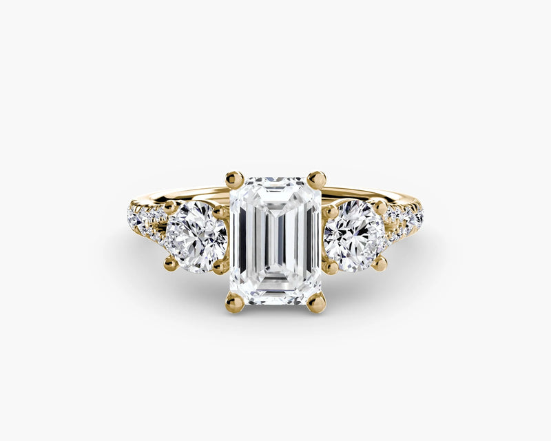 gold ring with a large emerald-cut diamond and smaller round diamonds on a white background