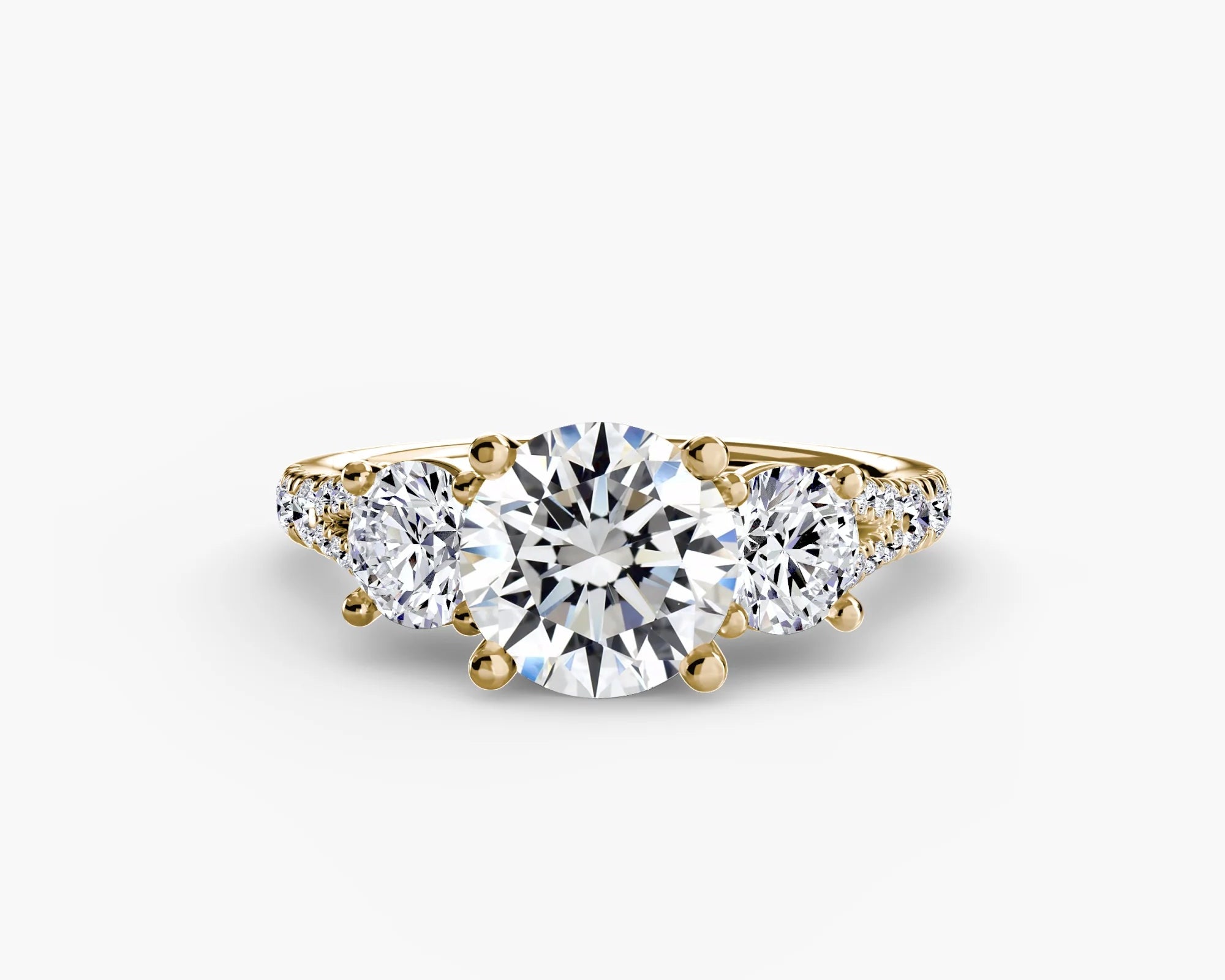Gold ring with a large central diamond and two smaller diamonds on either side against a white background