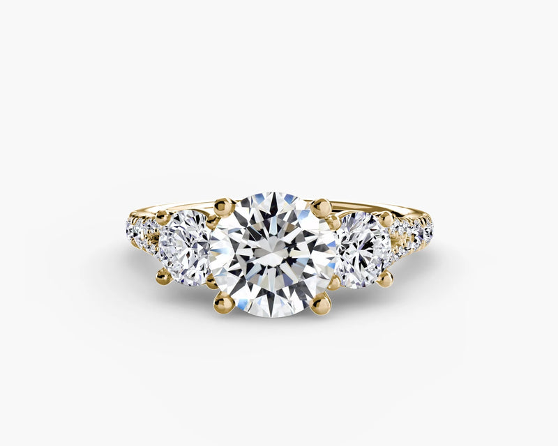 Gold ring with a large central diamond and two smaller diamonds on either side against a white background